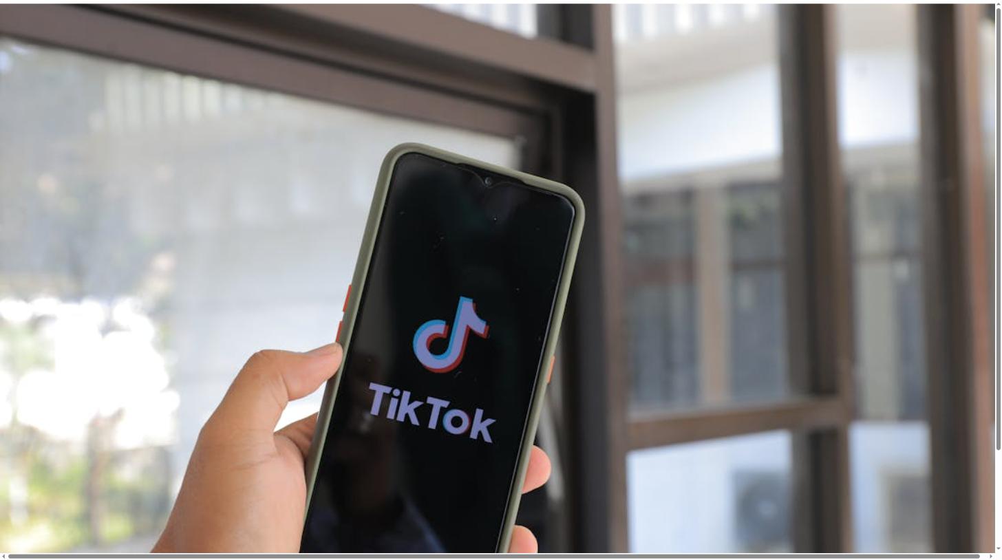 A hand holding a smartphone displaying the TikTok logo, representing scaling a TikTok Shop in 2026